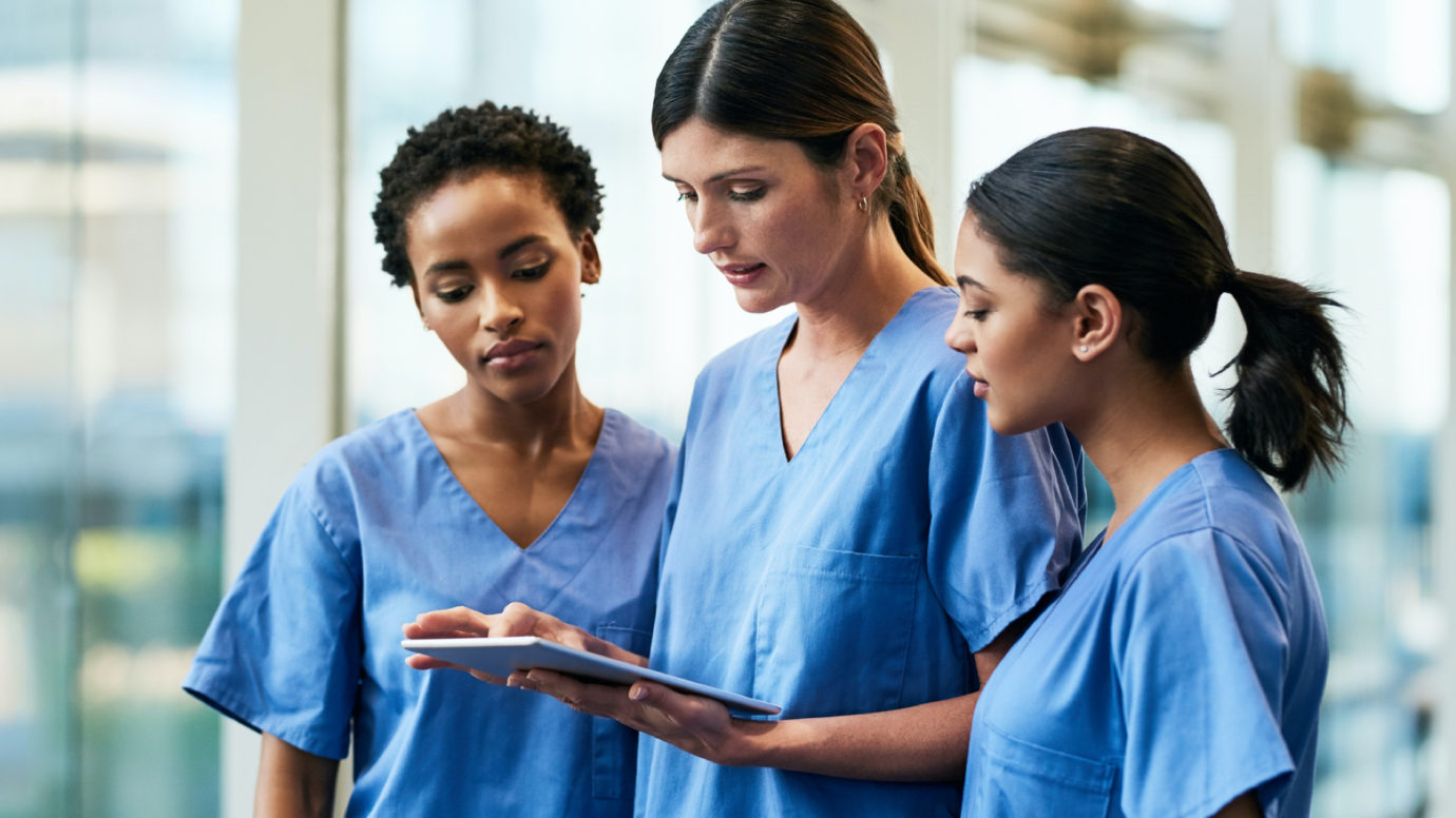 three nurses looking at a tablet