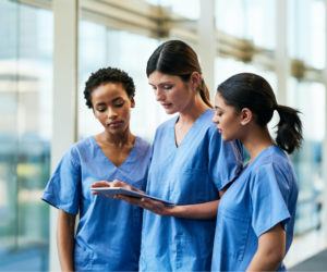 three nurses looking at a tablet