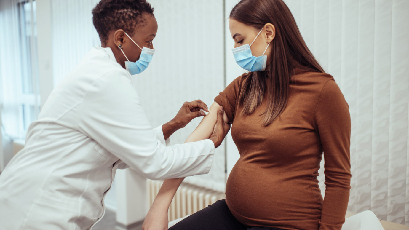 African American female doctor preparing a pregnant woman for vaccination