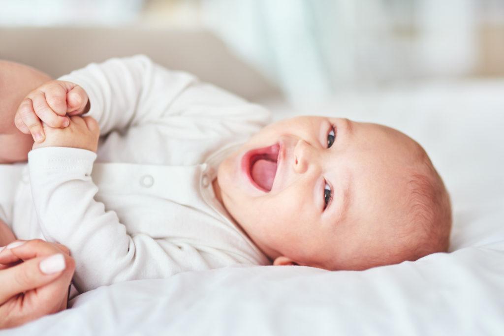 baby laughing while laying on the bed