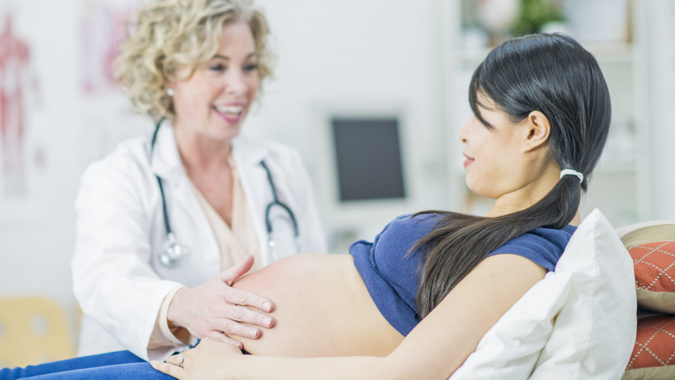 doctor touching pregnant women's belly